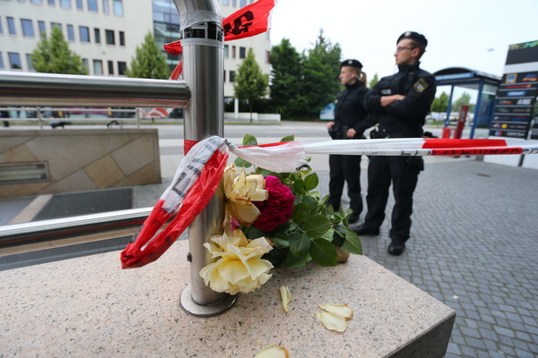 Blumen liegen am 23.07.2016 am Zugang zur U-Bahnstation Olympia-Einkaufszentrum in München (Bayern), den die Polizei nach einer Schießerei mit Toten und Verletzten am Vortag abgesperrt hat. Die tödlichen Schüsse hat ein 18-jähriger Deutsch-Iraner abgegeben. Zehn Menschen starben, darunter der Täter. Der Schütze, ein 18-jähriger Deutsch-Iraner, habe mit hoher Wahrscheinlichkeit alleine gehandelt und sich danach selbst erschossen, teilten die Ermittler am frühen Samstagmorgen mit. Foto: Karl-Josef Hildenbrand/dpa |/ Picture Alliance, rankfurt/Main 