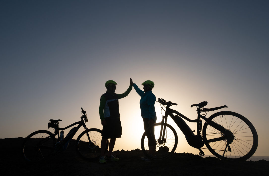 Elderly couple of caucasian old man and woman enjoying riding in a spring sunset in front to the sea. happiness and smiles
