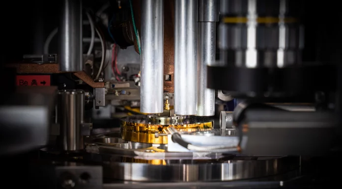 Weltrekord: Die Schweiz hält den Schlüssel zur Zukunft in der Hand Die Probe, ein zylinderförmiger Ausschnitt aus einem handelsüblichen Computerchip, wird von der goldfarbenen Nadel in der Mitte des Bildes gehalten. Mit einem Durchmesser von weniger als 0,000 005 Meter (etwa 20 Mal kleiner als die Breite eines menschlichen Haares) wurde sie mit einem fokussierten Ionenstrahl aus dem Chip herausgeschnitten und auf dem Stift platziert. © Paul Scherrer Institut PSI/Mahir Dzambegovic