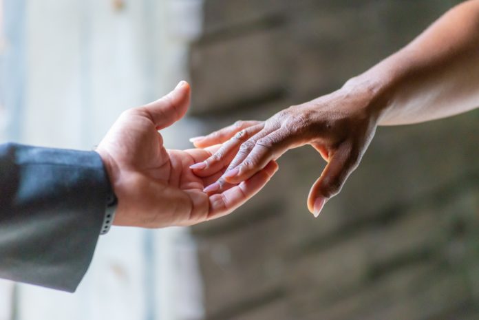 Closeup shot of the holding hands of an African American bride and caucasian groom