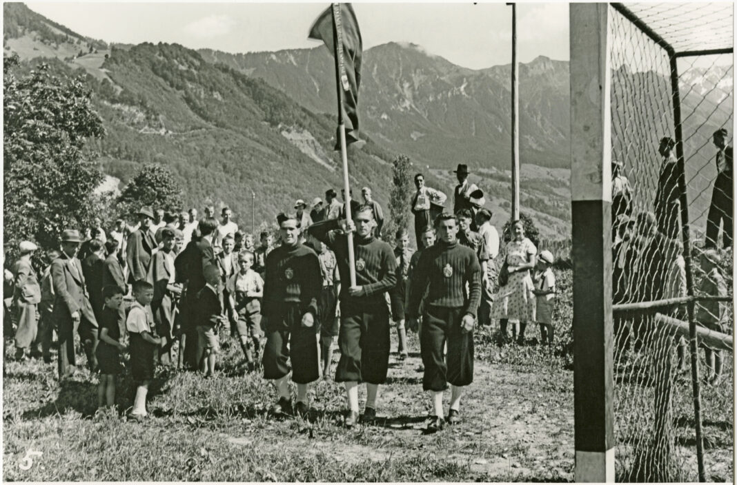 SgAV_01_B_025_150Teilnehmer der Winter-Olympiade in Garmisch-Partenkirchen, mit Fahne beim Einmarsch im Sommer, SgAV 01 B 025/150, Urheber: Unbekannt (Original); Walter Wachter, Schaan (Repro), Quelle: Liechtensteinisches Landesarchiv Vaduz, 1936